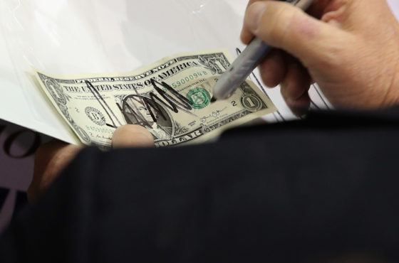 Trump signs a dollar bill for a supporter during a campaign rally at the Richmond International Raceway October 14, 2015 in Richmond, Virginia.