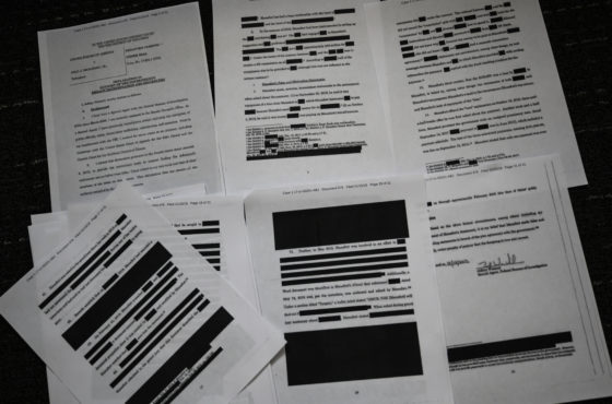 The pages of a redacted court filing from the Special Council Robert Mueller in the Paul Manafort case are spread out on a flat surface.