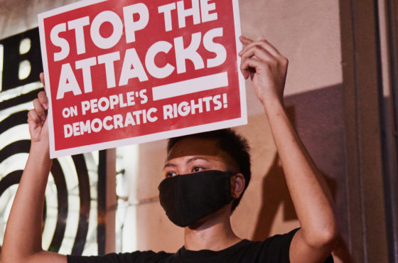 A person holds a sign reading, "Stop the Attacks on People's Democratic Rights!" in front of ABS-CBNs main office on May 5, 2020 in Manila, Philippines.