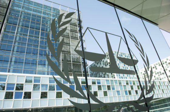 The ICC seal on a window at the International Criminal Court Building in The Hague. The windows act as mirrors, reflecting more of the ICC complex across from it.