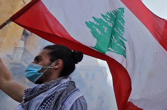A Lebanese protester waves a national flag amid clashes with security forces in the vicinity of Parliament in central Beirut on August 10, 2020.