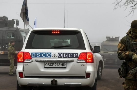 A car of the Organization for Security and Co-operation in Europe (OSCE) drives past Ukrainian servicemen in the settlement of Odradivka prior to a prisoner exchange between Ukraine and pro-Russian rebels on December 29, 2019.