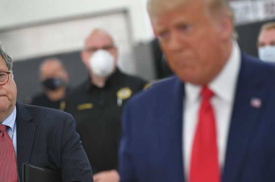 William Barr (unmasked) listens to Donald Trump (unmasked) speak on September 1, 2020, at Mary D. Bradford High School in Kenosha, Wisconsin. Police in the background wear masks.
