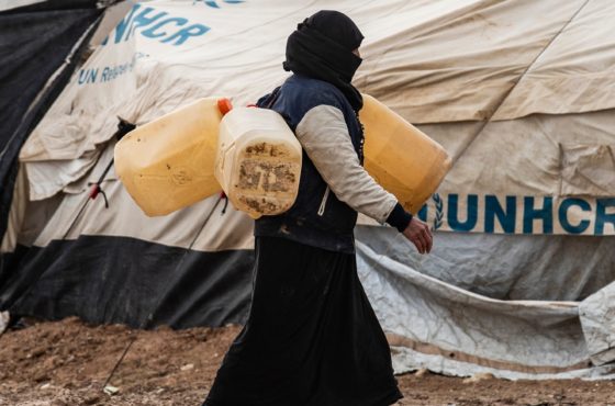 A woman carries jerry cans to fill them up with water at the Kurdish-run al-Hol camp for the displaced where families of Islamic State (IS) foreign fighters are held, in the al-Hasakeh governorate in northeastern Syria on December 9, 2019.