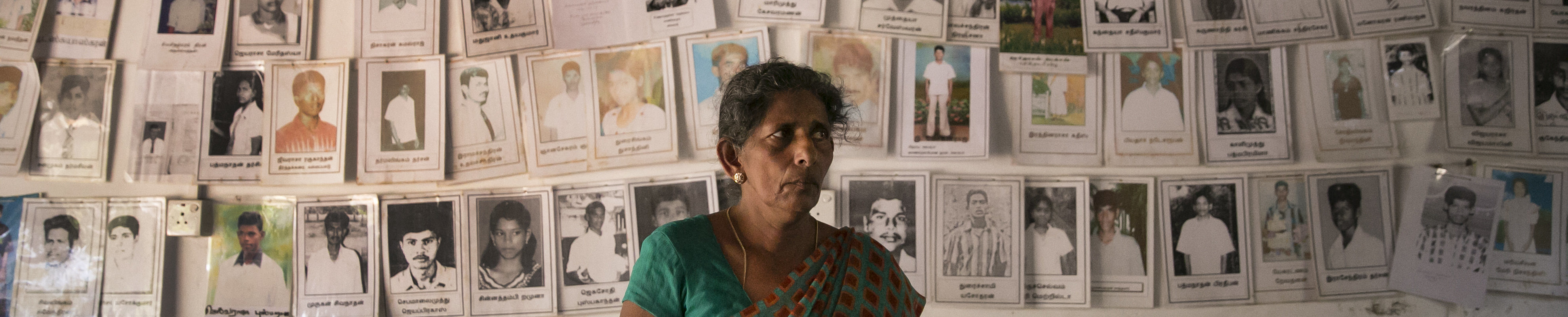Patmanathan Kokilavani holds photos of her two children at a protest site for loved ones of the disappeared on May 13, 2019 in Mullaitivu, Sri Lanka. Behind her are numerous photos strung on a wall of others who are disappeared.