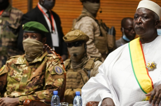 Transition Mali President Bah Ndaw without a face mask is seen with Malii Interim Vice President Colonel Assimi Goita, who wears a face, mask during his inauguration ceremony at the CICB (Centre International de Conferences de Bamako) in Bamako on September 25, 2020. Other soldiers with face masks sit and stand behind the two.