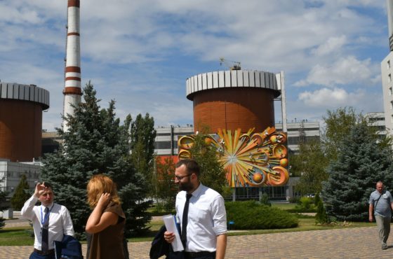 Three people walk and talk along a tree and grass-lined path at the Yuzhnoukrainska Nuclear Power Plant on June 19, 2018. One of the power plant’s cylindrical towers is covered in a sculptural art piece. The 3rd unit of Yuzhnoukrainsa Nuclear Power Plant is the first one in Ukraine loaded with a full core of nuclear fuel delivered by the Westinghouse Electric Company (USA).