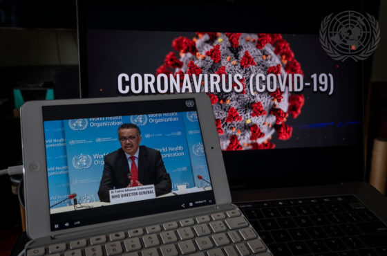 Tedros Adhanom Ghebreyesus, Director-General of the World Health Organization (WHO), holds a virtual briefing on the COVID-19 pandemic. His briefing is viewed on an iPad, and a separate computer screen behind the iPad shows a 3-D rendering of the coronavirus with the words, “Coronavirus (COVID-19)”