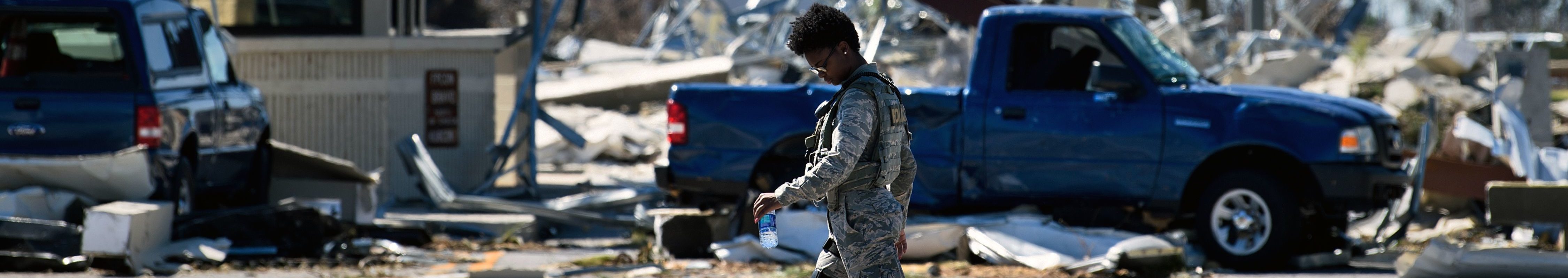 A military police officer walks near a destroyed gate in Tyndall Air Force Base, in Florida in the aftermath of Hurricane Michael on October 12, 2018. Rubble from the gate covers the floor. The two guard booths on either side of the former gate appear damaged, but are still standing.
