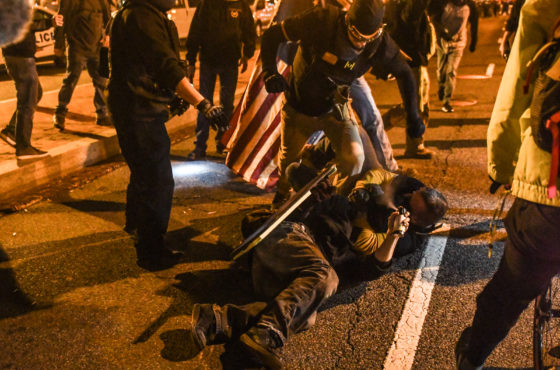 Members of the Proud Boys kick an anti-fascist protestor on the ground during a protest on December 12, 2020 in Washington, DC. Additional white supremacists stand around watching.