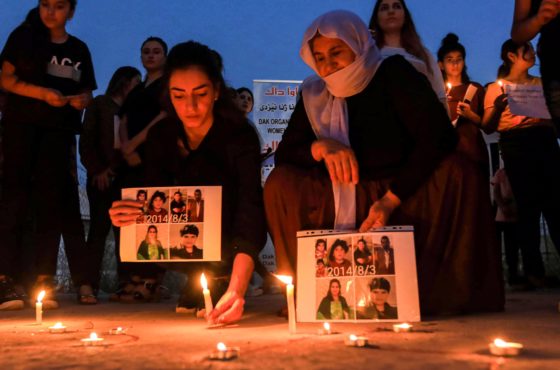 Iraqi Yazidis attend a candle-lit vigil in the Sharya area, some 15 kilometres from the northern city of Dohuk in the autonomous Iraqi Kurdistan region on August 3, 2020, marking the sixth anniversary of the Islamic State (IS) group's attack on the Yazidi community in the northwestern Sinjar district. Candles are placed on the ground and people hold pictures of those who died.