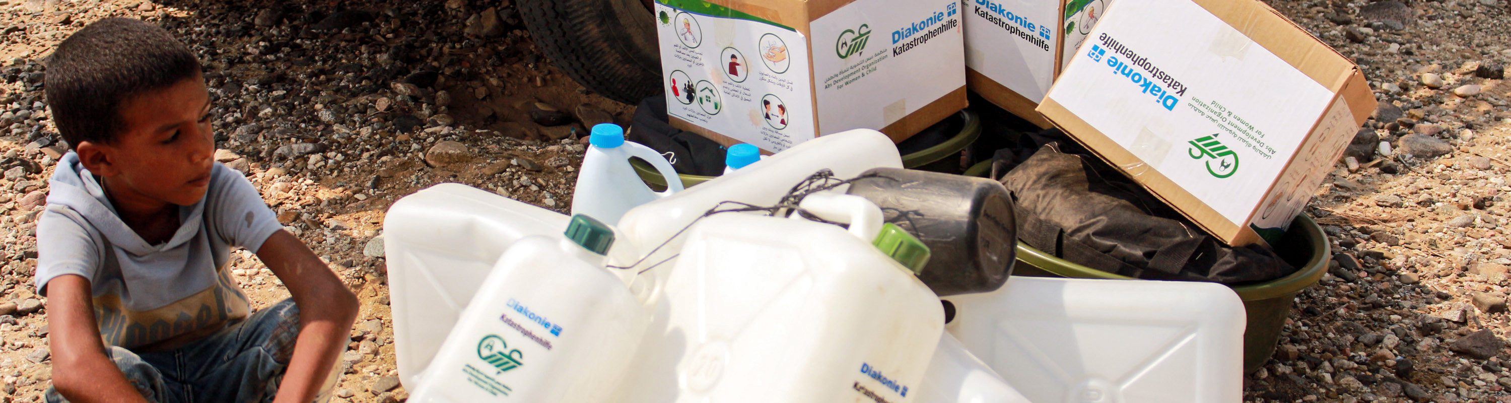 A child waits next to jerry cans and aid packages as Yemenis displaced by conflict receive huamnitarian aid provided by the Abs Development Organisation (ADO) in the northern province of Hajjah on September 17, 2020.