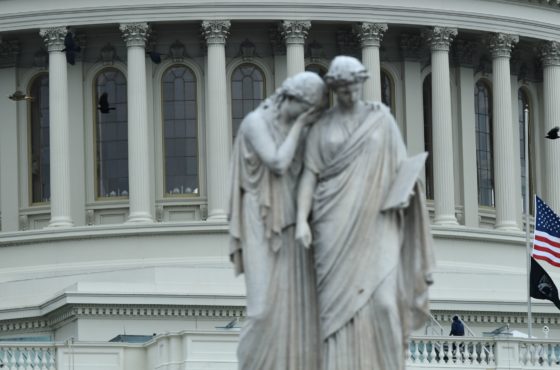 Statues in front of the US capitol building. Behind the statues, flags at the US Capitol fly at half-mast to honor US Capitol Police Officer Brian Sicknick, on January 8, 2021, in Washington, DC. Sicknick died from injuries sustained during the attempted coup on January 6th.