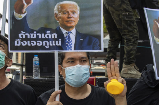 Pro-democracy protesters hold up a sign showing a meme of U.S. President Elect Joe Biden and "No 112" on them during a rally at the Nonthaburi Police Station on December 08, 2020 in Bangkok, Thailand.