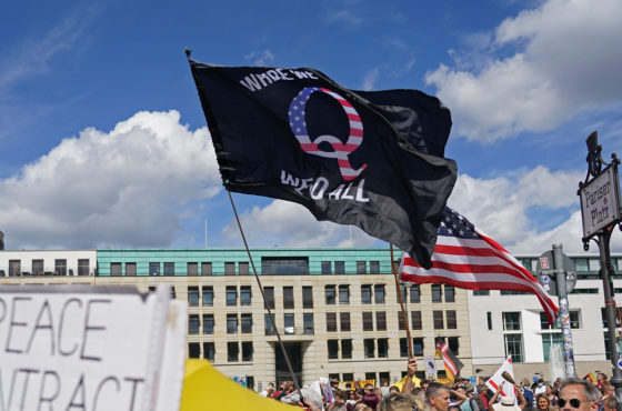 A man waves a QAnon conspiracy flag at a protest of coronavirus skeptics, right-wing extremists and others angry over coronavirus-related restrictions and government policy on August 29, 2020 in Berlin, Germany. People do not wear face masks.
