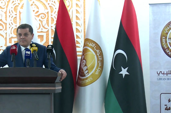 Libya's new interim Prime Minister Abdul Hamid Dbeibah speaks after being sworn in on March 15, 2021 in the eastern coastal city of Tobruk. Multiple flags of Libya stand behind him.
