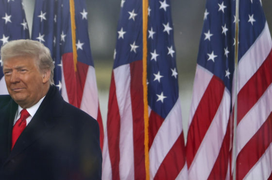 Trump gestures in front of a line of American flags at the "Stop The Steal" Rally on January 06, 2021 in Washington, DC.