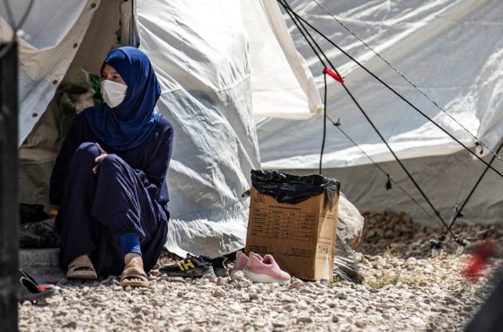 A woman clad in mask due to the COVID-19 coronavirus pandemic, sits outside a tent near a water cistern at Camp Roj, housing family members of people accused to belong to the Islamic State (IS) group who were relocated from al-Hol camp, in the countryside near al-Malikiyah (Derik) in Syria's northeastern Hasakah province on September 30, 2020.