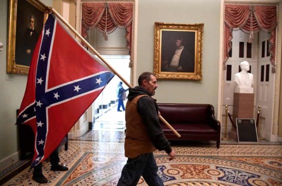 A white supremacist walks through the halls of the Capitol Building with a confederate flag during the insurrection on January 6, 2021.