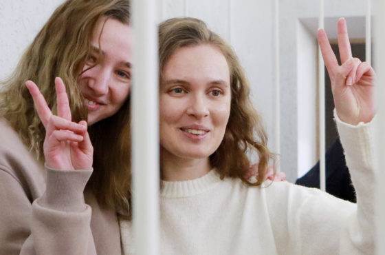 Belsat TV journalists Katerina Bakhvalova aka Andreeva and Daria Chultsova, who were detained in November while reporting on anti-government protests, flash the V-sign from a defendant's cage during their trial in Minsk on February 18, 2021.