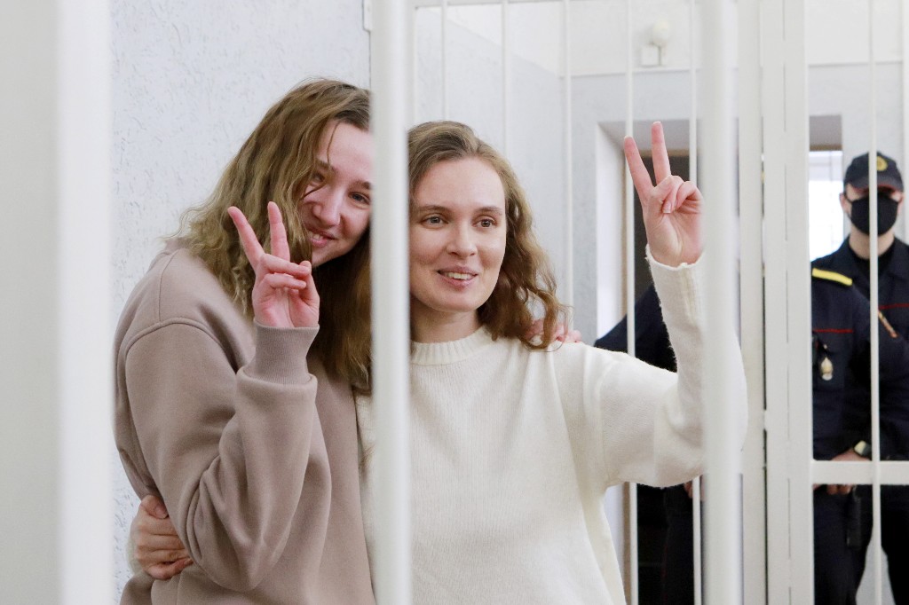 Belsat TV journalists Katerina Bakhvalova aka Andreeva and Daria Chultsova, who were detained in November while reporting on anti-government protests, flash the V-sign from a defendant's cage during their trial in Minsk on February 18, 2021.