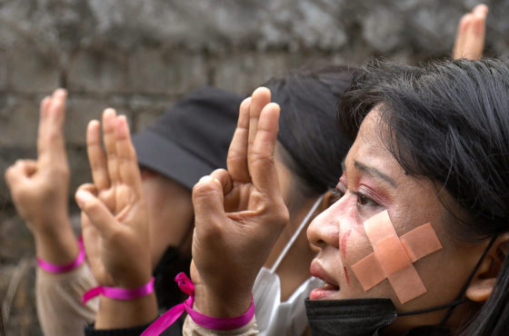 Protesters, wearing red make-up to simulate tears of blood, make the three-finger salute during a demonstration against the military coup in Yangon's Hlaing township. They wear pink ribbons around their wrists.