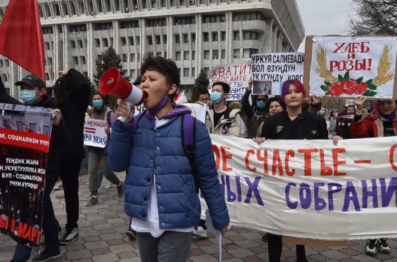 People carry banners as they attend a rally to mark the International Women's Day in Bishkek on March 8, 2021. Some people wear face masks but not all.