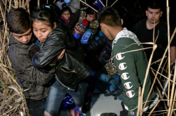 Young refugees from Honduras and Guatemala walk through marsh land around the Rio Grande river as they disembark an inflatable boat on March 28, 2021.