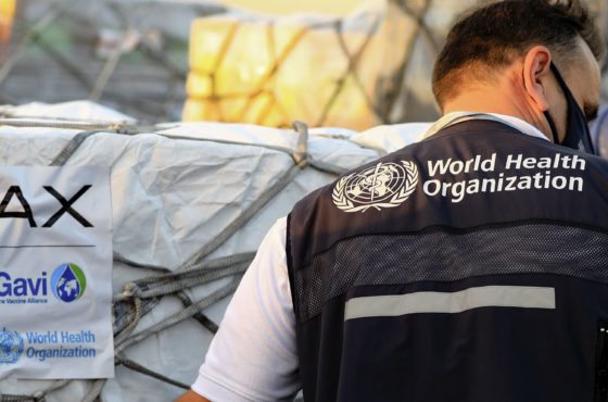 An employee, wearing a face mask and a WHO vest, of the World Health Organisation (WHO) supervises the arrival of the first batch of coronavirus vaccines, at Khartoum airport in the Sudanese capital, on March 3, 2121.